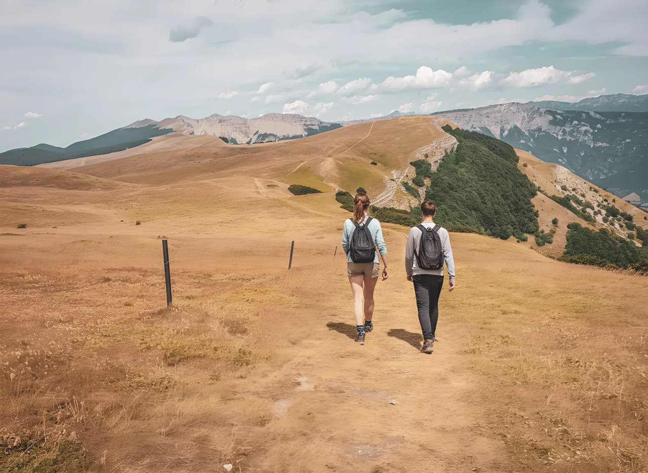 Deux randonneurs explorent des paysages dorés et vallonnés, plongeant dans la nature du Vercors.