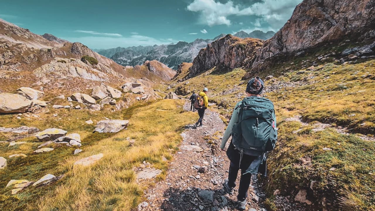Randonnée dans les Hautes Pyrénées, chemin bordé de rochers, paysage montagnard époustouflant.