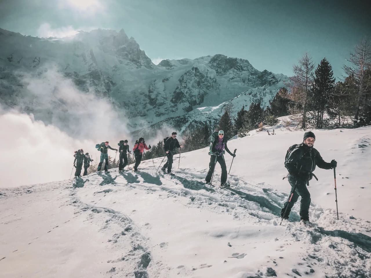 A group of snowshoe hikers on a snowy trail, facing the majestic glaciers of the Écrins.