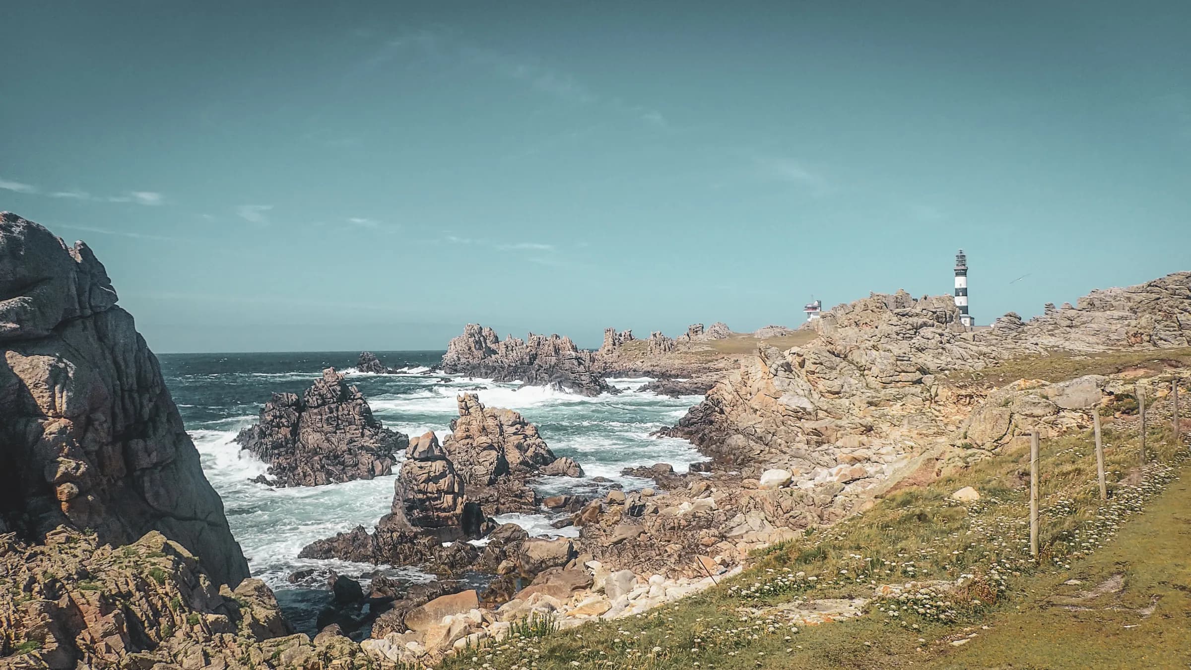 A wild coastal landscape in the Molène archipelago, with rocks, rough seas and a lighthouse.