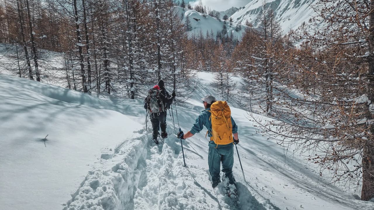 Two hikers on snowshoes covering virgin snow in Haute-Ubaye, under a sunny sky.