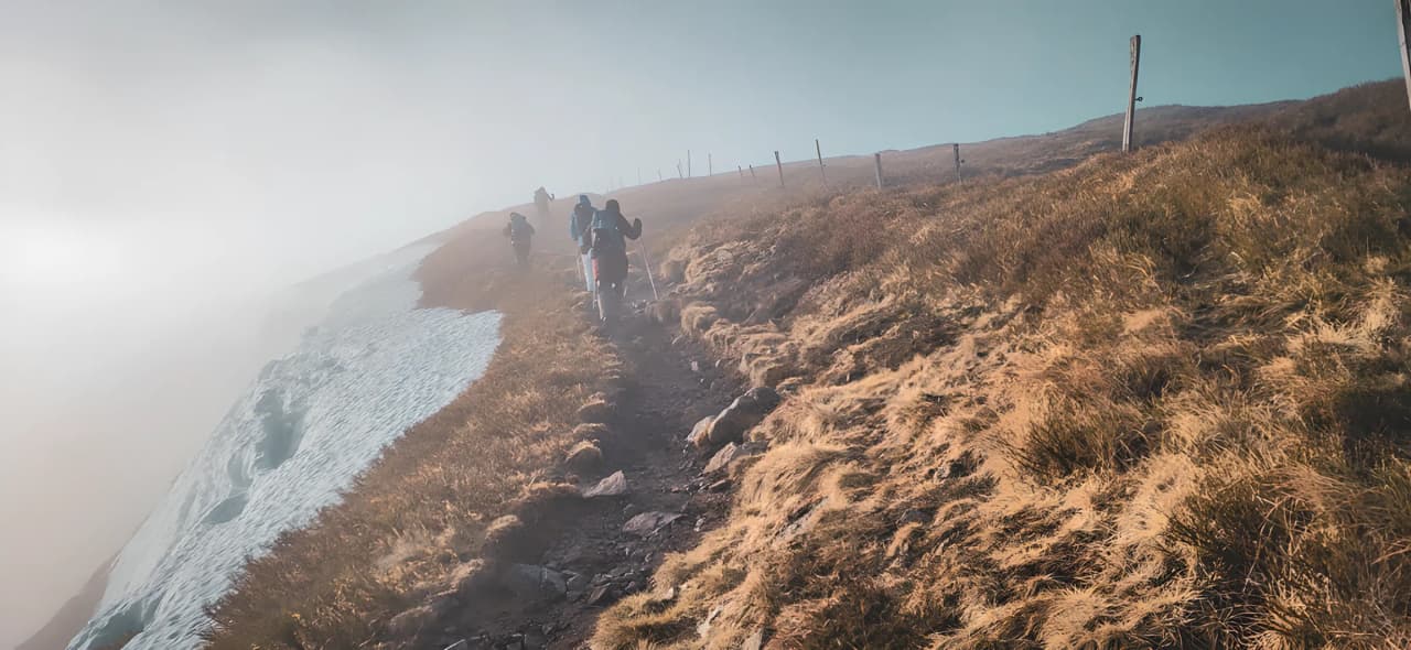 A group of hikers on a trail in the Vosges, surrounded by mist and snowy landscapes.