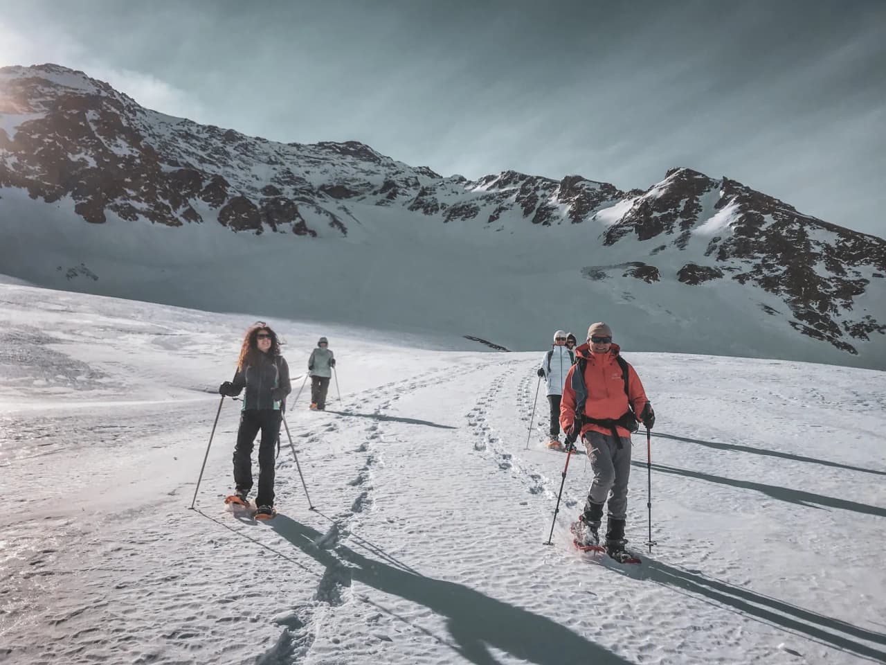 Group snowshoeing on a glacier, majestic snowy landscapes in the background.
