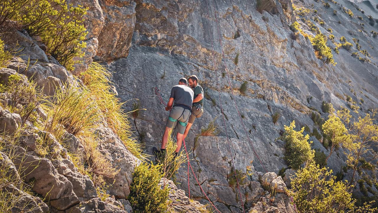 Two mountaineers are preparing to climb a majestic rock face on Mont Aiguille.