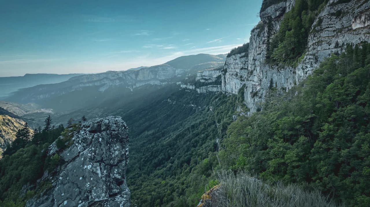 Randonneur explorant les paysages montagneux du Vercors, entre prairies verdoyantes et sommets.