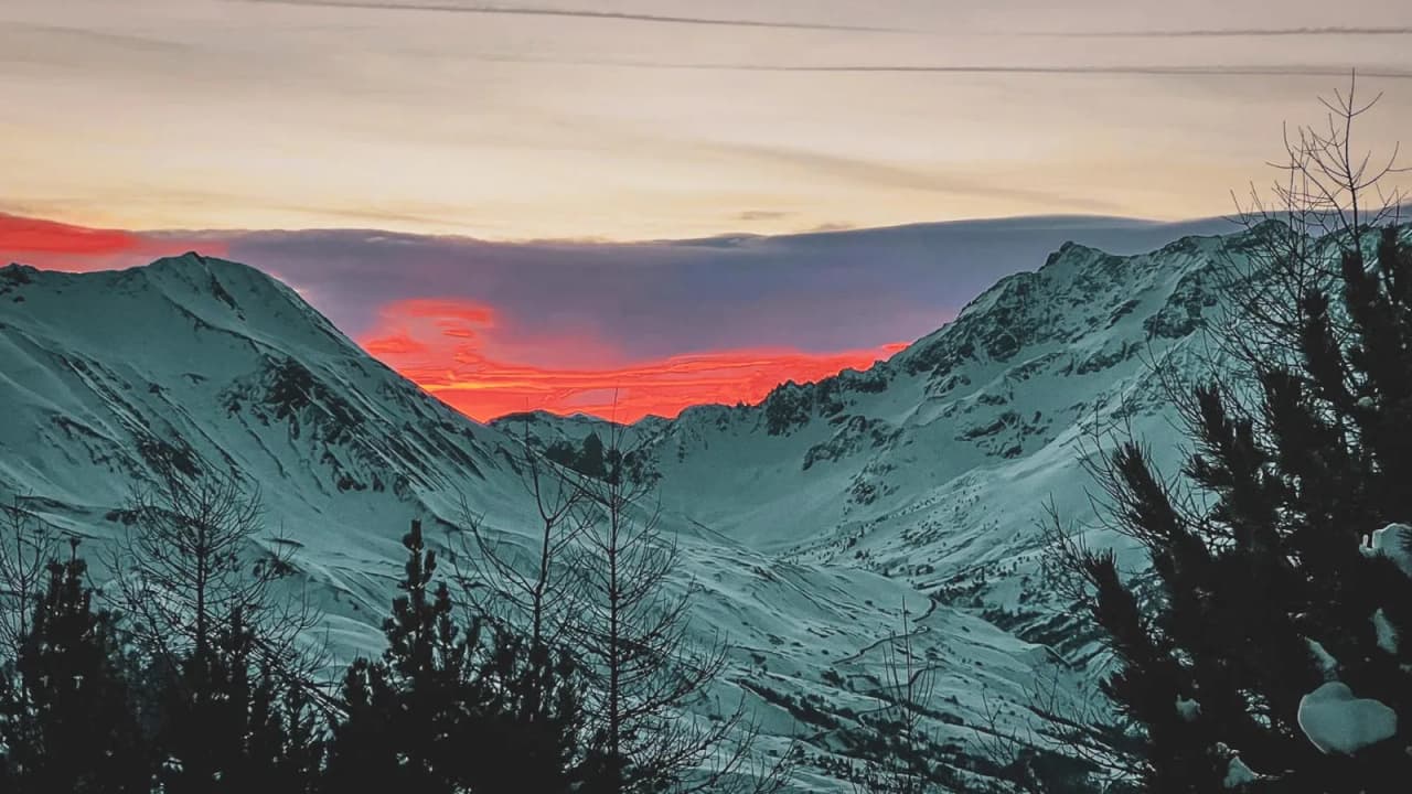A vibrant sunset over the snow-capped peaks of the Cerces, promising adventure and magic.