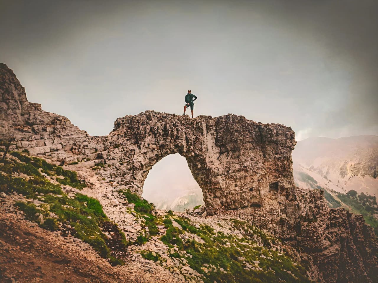 A climber stands on a majestic rock, offering a panoramic view of Mont Aiguille.