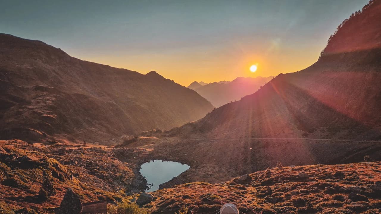 Coucher de soleil sur les montagnes pyrénéennes, reflet paisible dans un lac alpin.