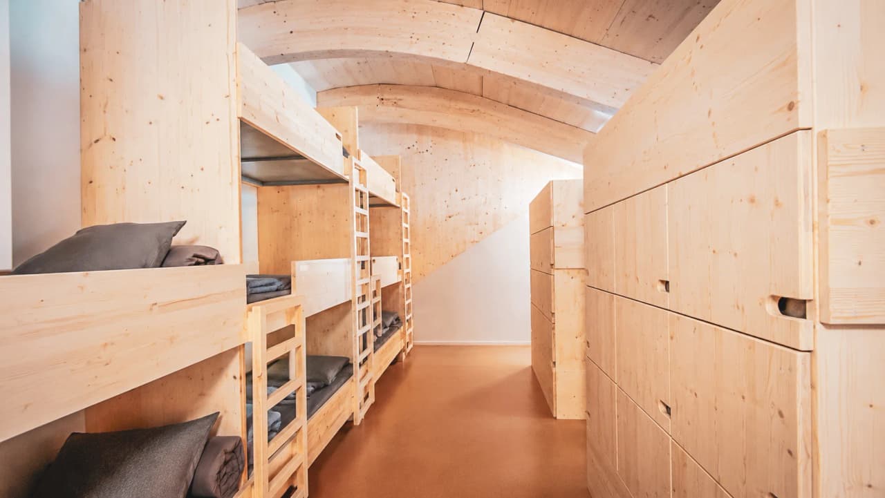 Intérieur moderne en bois d'un refuge de montagne, avec lits superposés et ambiance chaleureuse.
