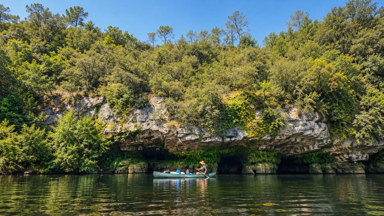 Canoë paisible sur la Dordogne, entouré de falaises verdoyantes et d'une nature sauvage.
