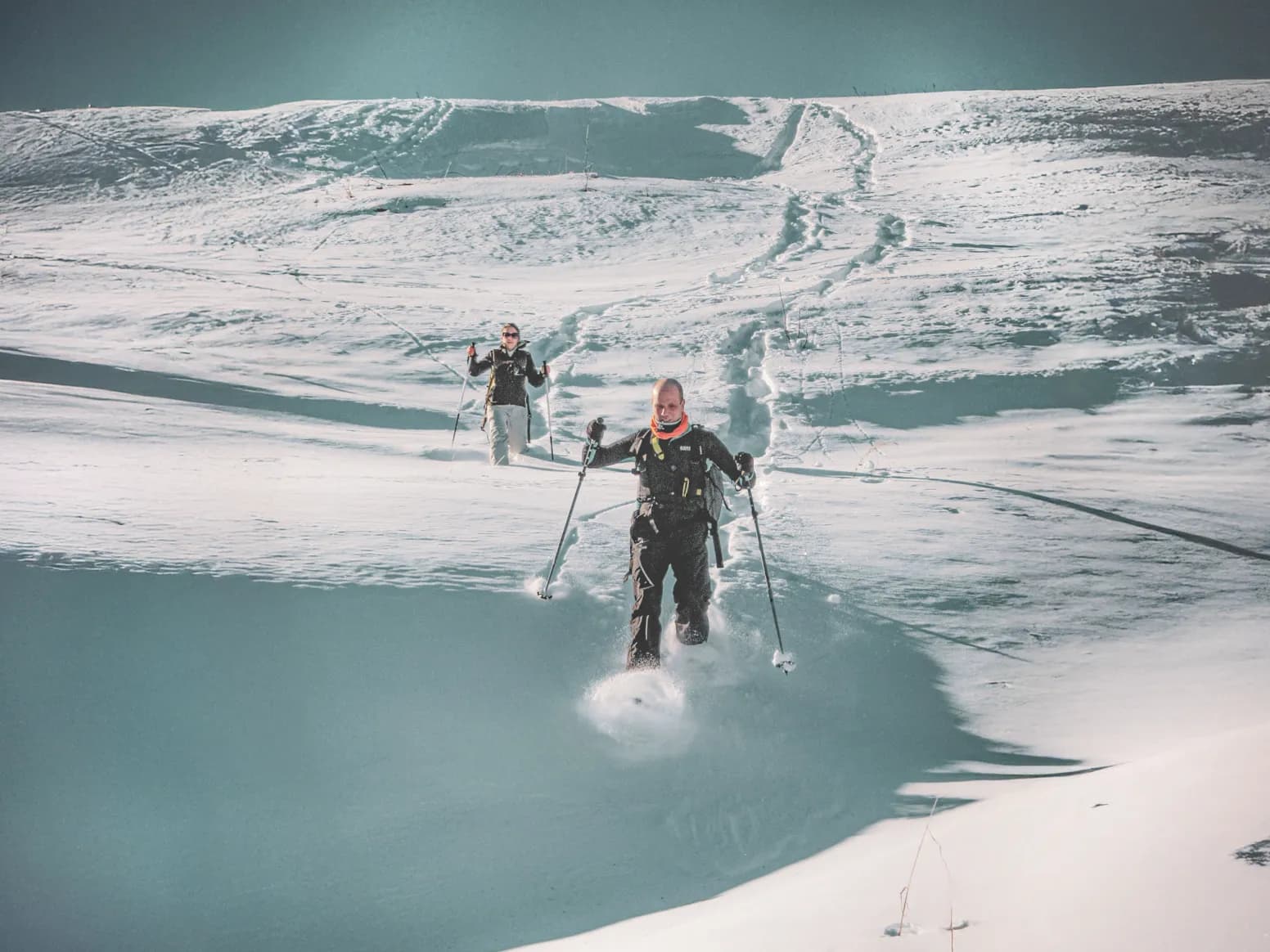 Two hikers on snowshoes make their way through the virgin snow of the Clarée valley, under a clear sky.