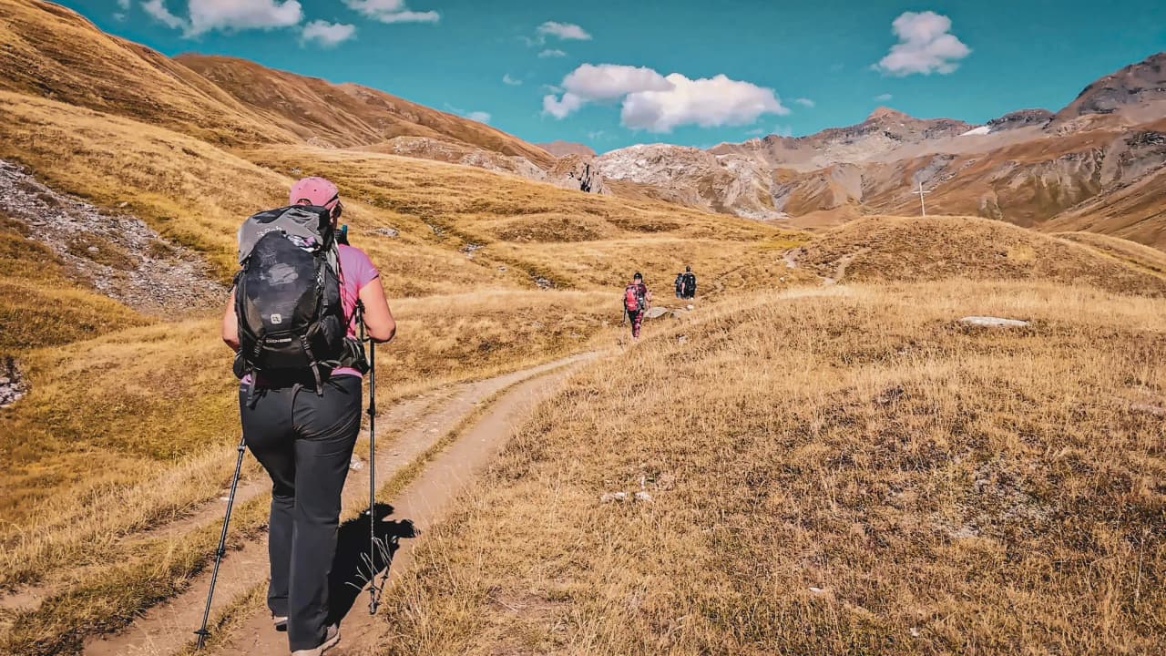 Groupe de randonneurs dans les paysages dorés du Parc National de la Vanoise, ciel bleu et liberté.