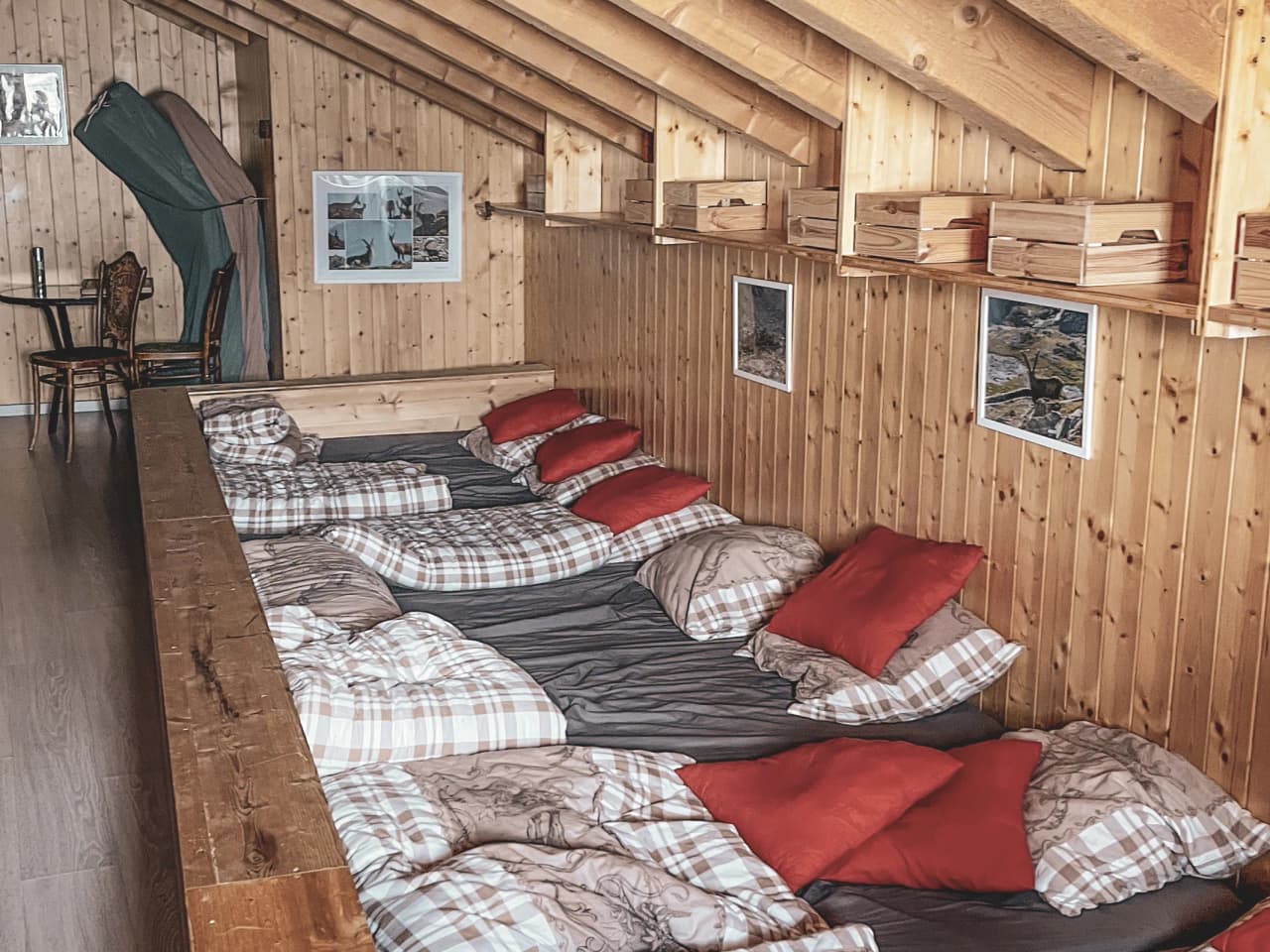 A cosy wooden dormitory with colourful cushions, perfect for relaxing after a day on the slopes.