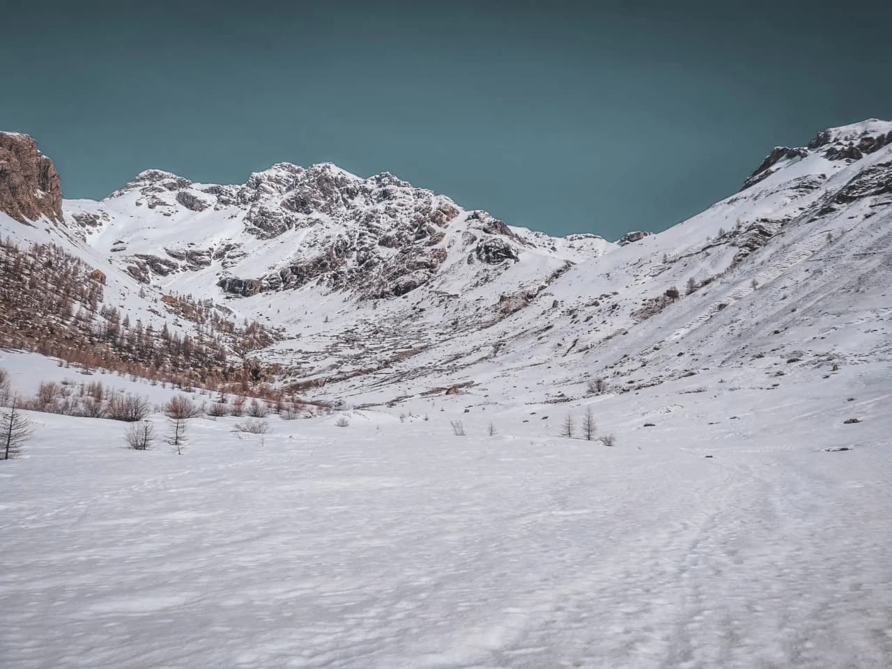 A spectacular snowy landscape with majestic mountains under a blue sky.