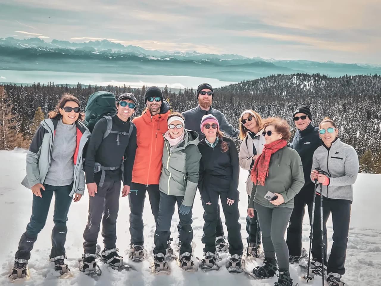 A happy group on snowshoes, with mountains in the background, ready for adventure.
