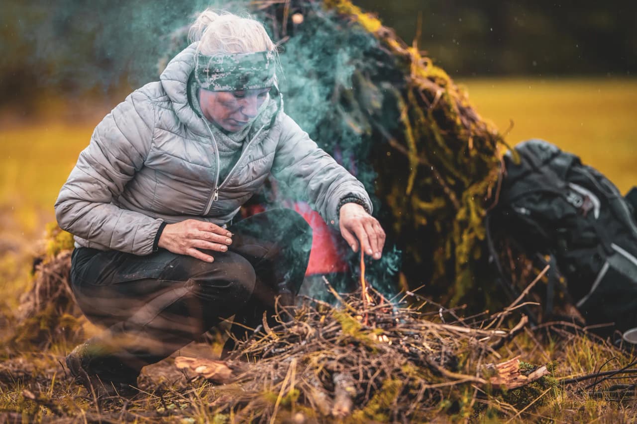 Une personne allumant un feu dans la nature, entourée d'une forêt verdoyante et paisible.