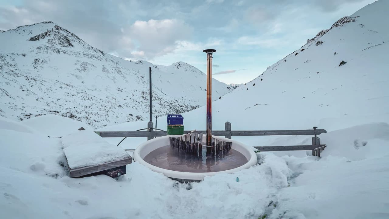 A welcoming heated bath surrounded by snow-capped mountains, an invitation to alpine adventure.