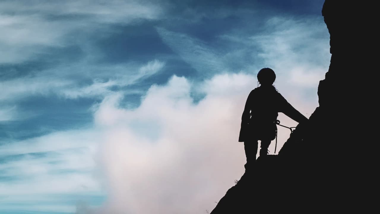 The silhouette of a climber on Mont Aiguille, clear skies, the promise of adventure and breathtaking panoramas.